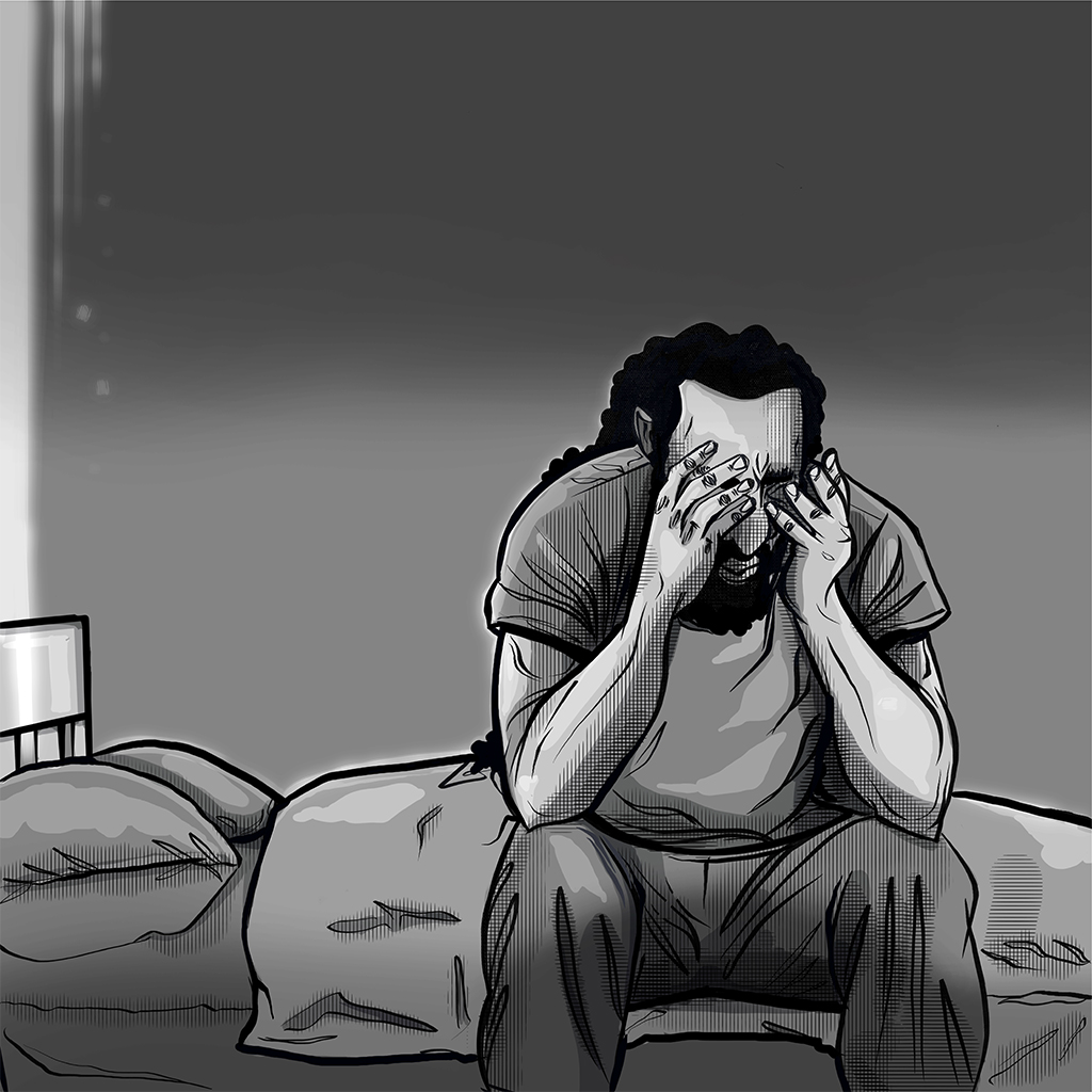 A hopeless man seated on the edge of his bed with his head in his hands.